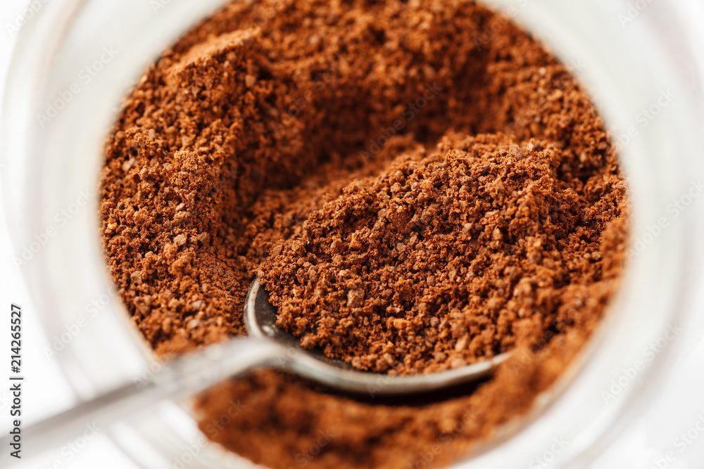 Ground natural coffee inside of glass jar with metal spoon, macro Ground natural coffee inside of glass jar with metal spoon, macro