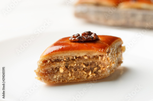 Oriental sweets with walnut in a white plate on a wooden table, closeup