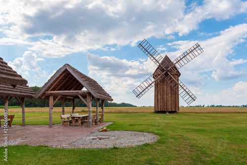 Traditional wooden architecture and old windmill on field in Poland. © vivoo