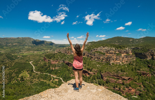 Backpacker adventurer girl admiring the landscape from top of a cliff