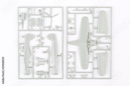 kit for assembling gray plastic airplane model on white bsckground