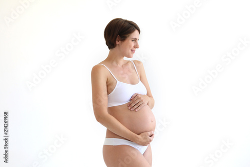Hübsche schwangere Frauhält sich lächelnd den Bauch und schaut in eine Richtung © Joerch
