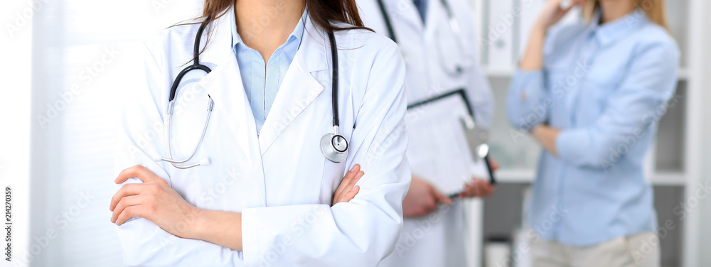 Female doctor standing straight in hospital. Closeup of stethoscope at practitioner breast. Medicine and health care concept Female doctor standing straight in hospital. Closeup of stethoscope at practitioner breast. Medicine and health care concept