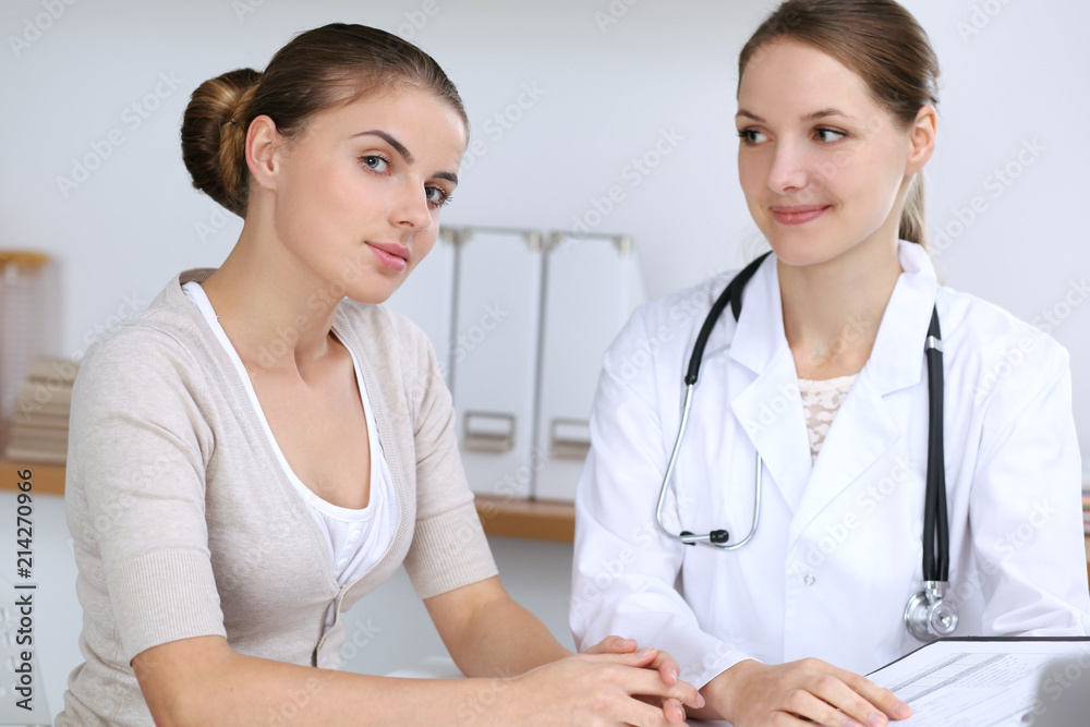 Doctor and patient having a pleasure talk while sitting at the desk at hospital office. Healthcare and medicine concept Doctor and patient having a pleasure talk while sitting at the desk at hospital office. Healthcare and medicine concept
