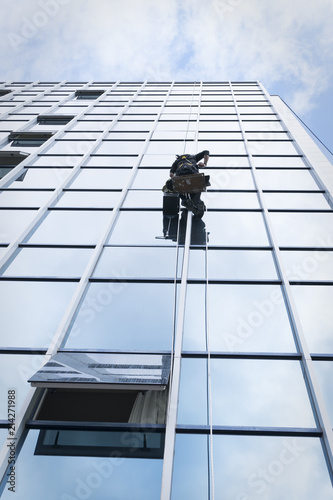 Window cleaner working on a glass facade suspended photo