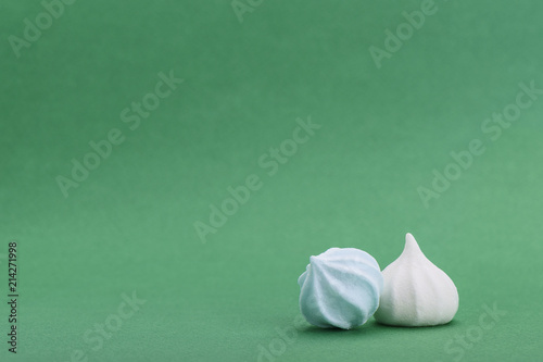 Blue and white meringues isolated on green background with space for text