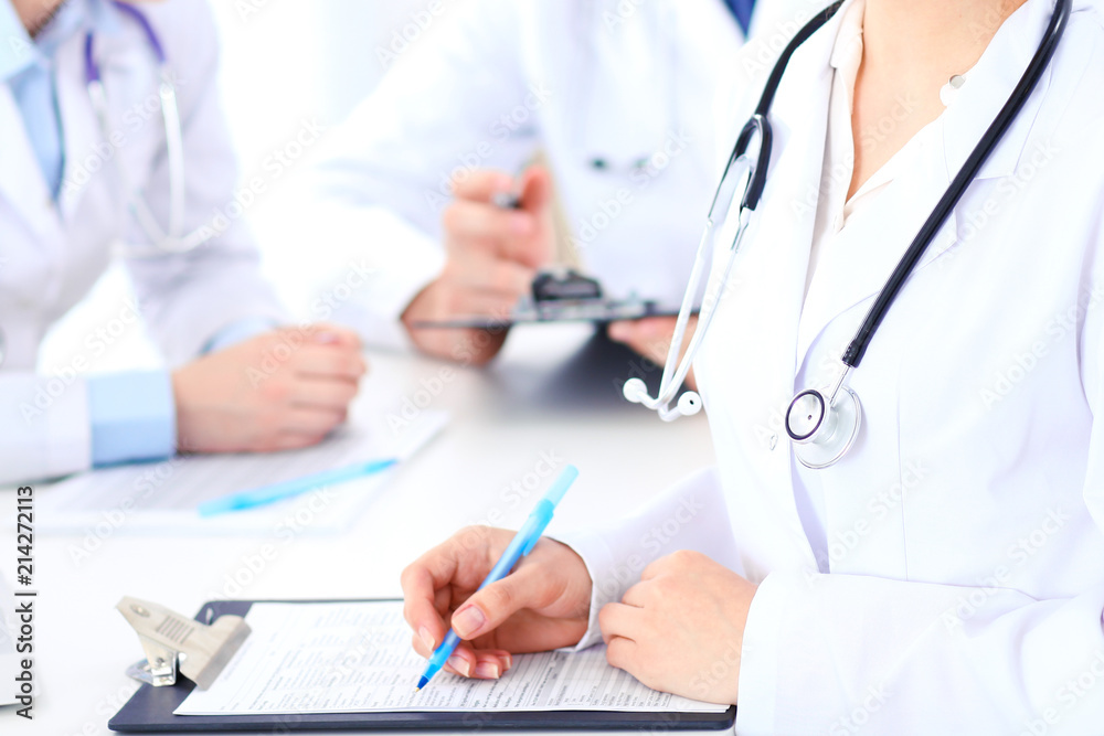 Group of unknown doctors working at hospital while sitting at the table. Teamwork and success concept in medicine Group of unknown doctors working at hospital while sitting at the table. Teamwork and success concept in medicine
