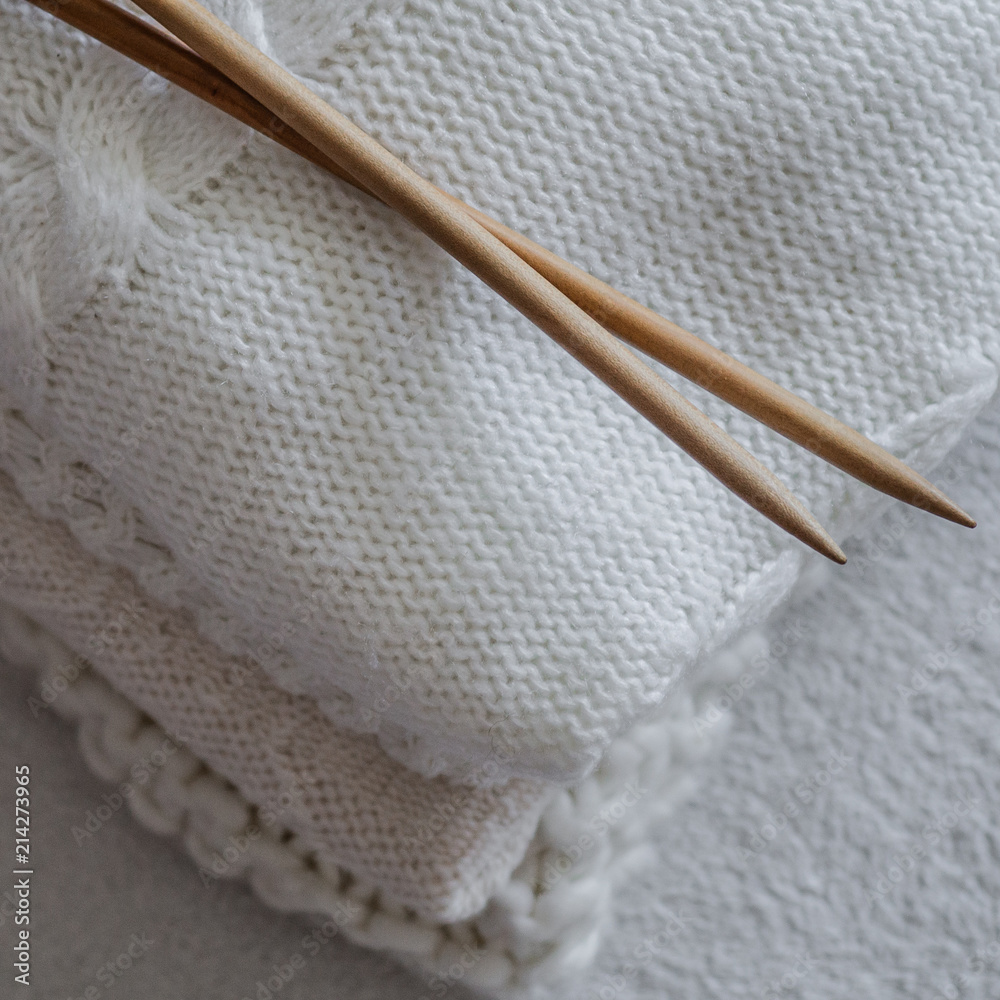 White sweaters and yarn for knitting close up. Knitting needles. Concept Handicraft. Place for text White sweaters and yarn for knitting close up. Knitting needles. Concept Handicraft. Place for text