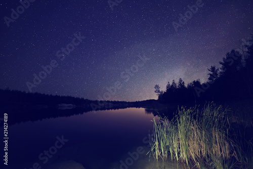 Lake at night with amazing starry sky and reflections in the water. Natural outddors travel dark background. photo