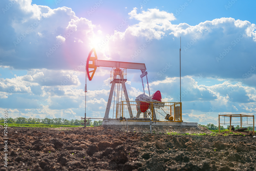 Oil rocking in the field against the cloudy sky with bright sun rays Oil rocking in the field against the cloudy sky with bright sun rays