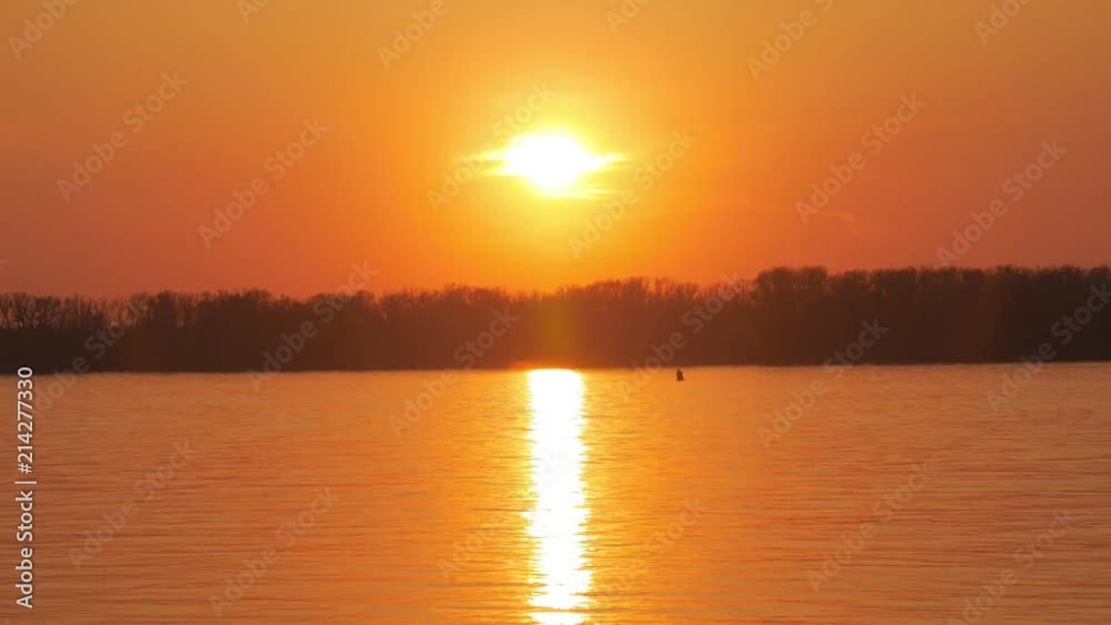 bright evening sun is over river and forest in sunset time