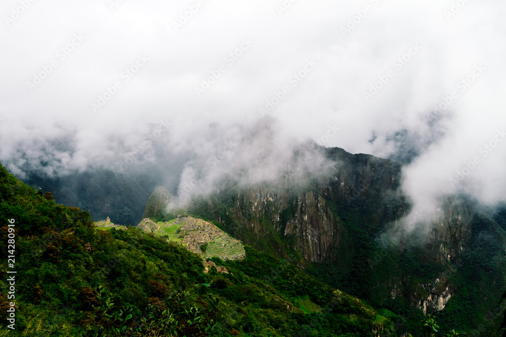 Distant view of Machu Picchu citadel among clouds with valley view
