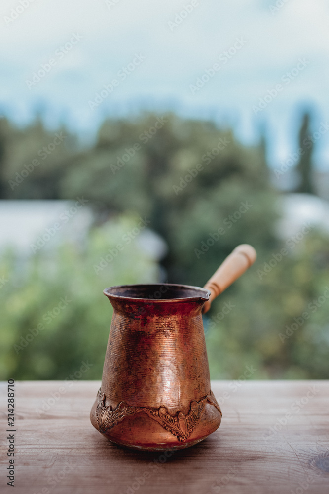 Cooper jezve with wooden handle as natural background Cooper jezve with wooden handle as natural background