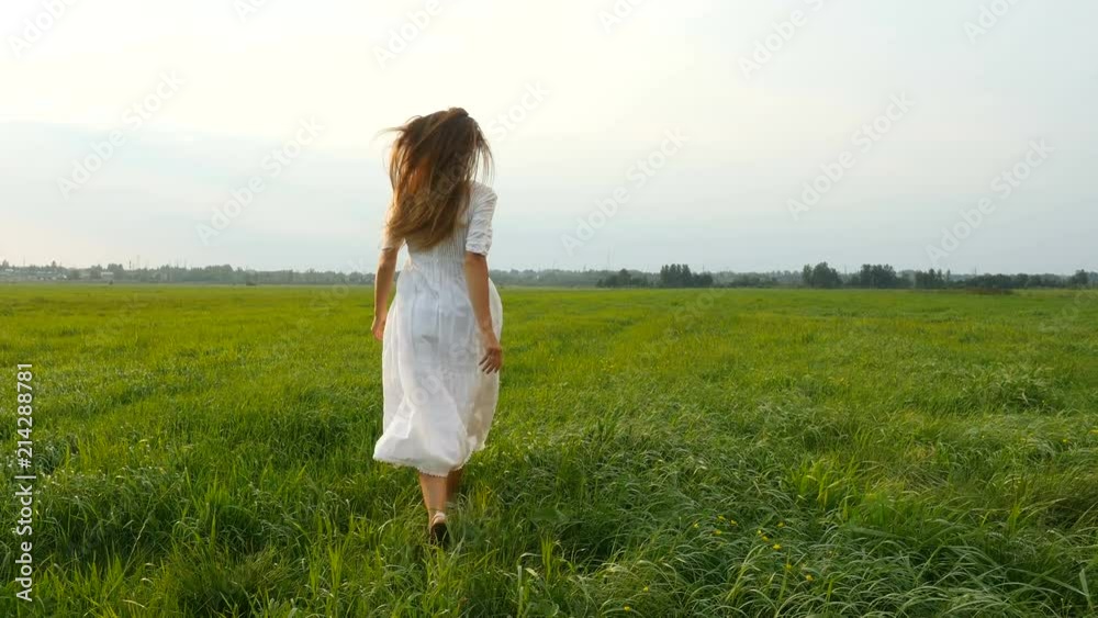 Beautiful woman running on the green grass. Wind blowing hair. Grassy summerfield Beautiful woman running on the green grass. Wind blowing hair. Grassy summerfield