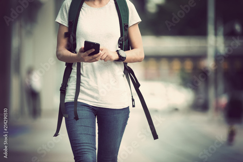 young woman walking with mobile phone in modern city photo