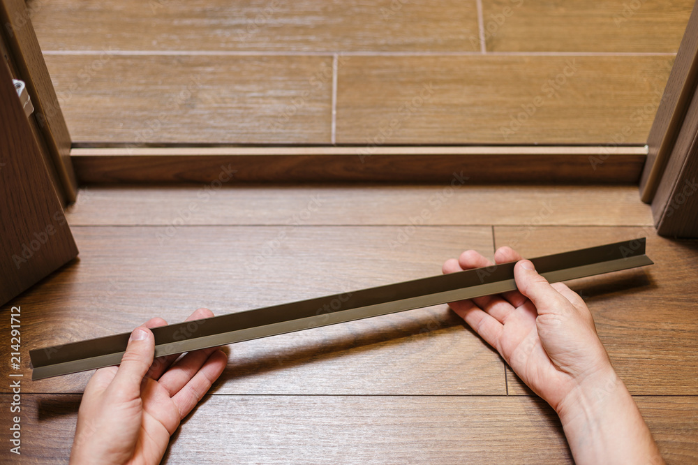 Obraz premium Repair, building and home concept. Construction worker fixing metal profile to the doorstep with adhesive. 