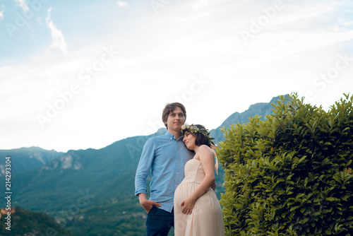 Portarit of happy couple. Pregnant woman with her husband outdoors. Beautiful scenic landscape. Lake Como, Italy