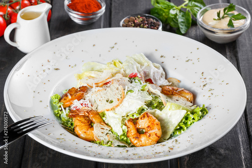Shrimp salad with parmesan cheese, croutons, tomatoes, mixed greens, lettuce on wooden background. Healthy food.