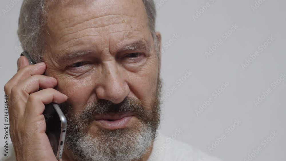 An Elderly Bearded Man Is Unhappy To Speak On A Smartphone An Elderly Bearded Man Is Unhappy To Speak On A Smartphone
