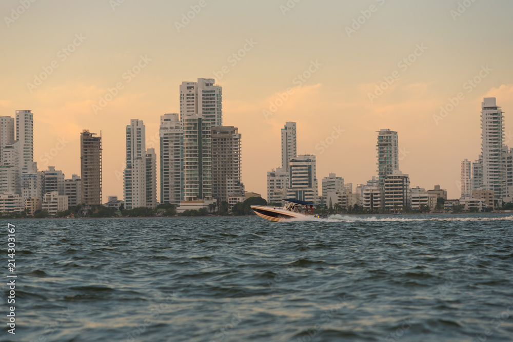 Fototapeta premium Fast boat at sunset on the coast of Cartagena with modern buildings in the background. Colombia