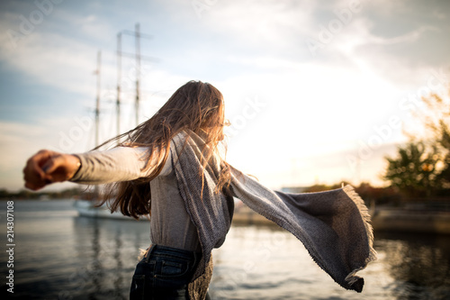 Photography girl dancing next to the waterfront at sunset