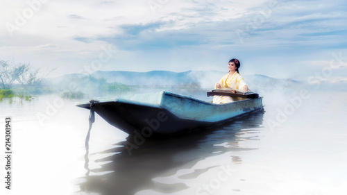 Chinese girl is playing the traditional Chinese musical instrument on the boats in the lake ;Chinese plucked zither a traditional chinese musical