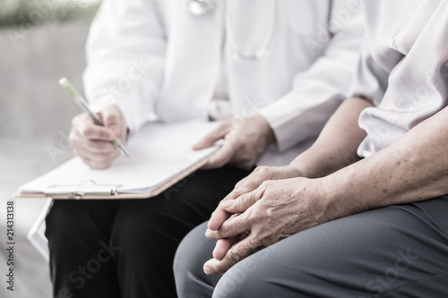 Parkinson and alzheimer female senior elderly patient with caregiver in hospice care. Old woman holding hand with doctor physician.