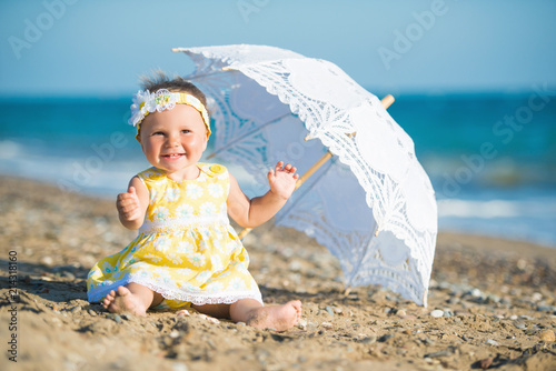 Lovely little girl on the beach with an umbrella photo