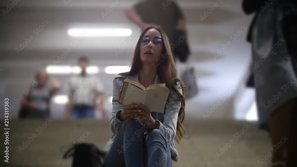 Girl sitting on the stairs in the subway and reading a book Girl sitting on the stairs in the subway and reading a book