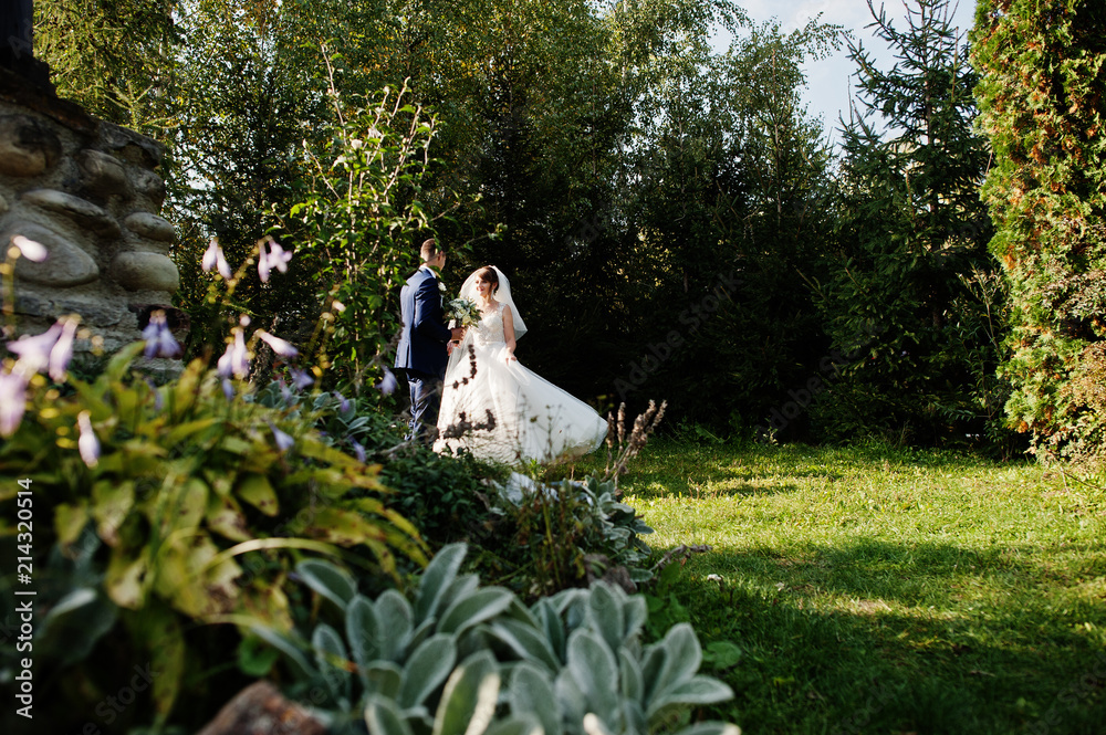 Young happy wedding couple posing outdoors in garden or in the park. Young happy wedding couple posing outdoors in garden or in the park.