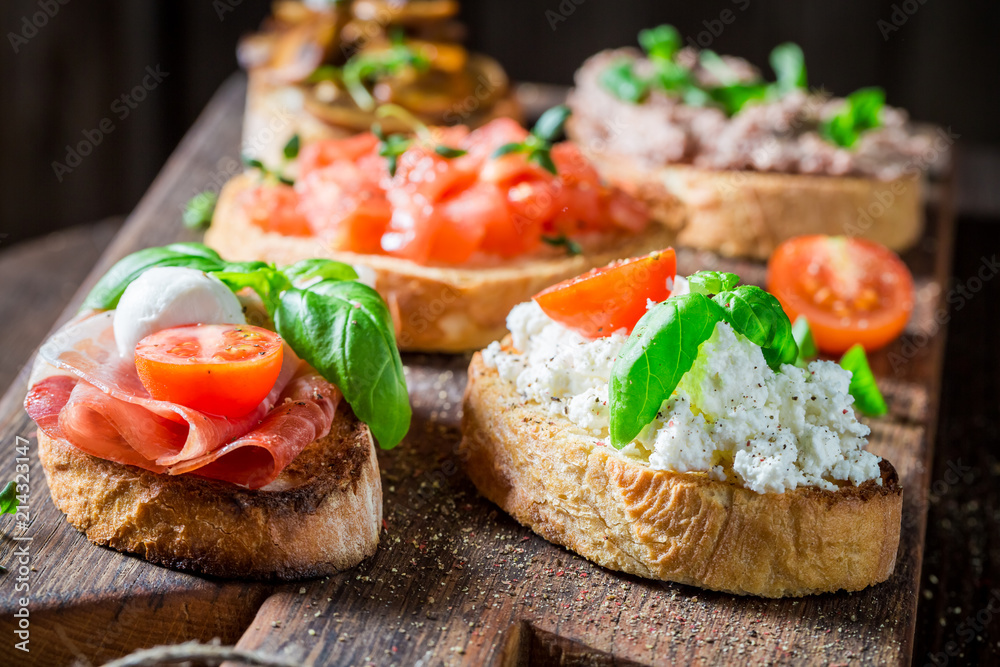 Delicious and tasty mix of bruschetta on old wooden table