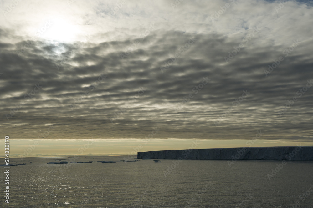 A beautiful silhouette of a very large iceberg in the Arctic under a cloudy sky