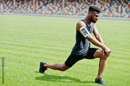 African american male athlete in sportswear doing stretching exercise at stadium. © AS Photo Family