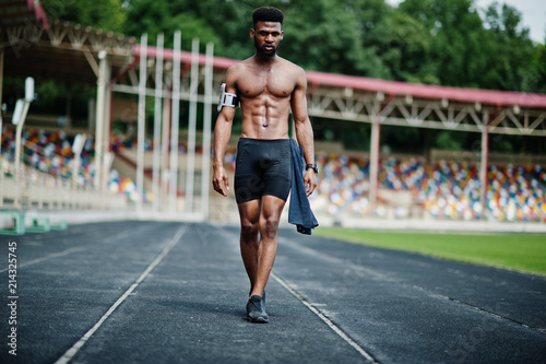 African american male athlete sexy sport bare torso man with running sports arm case for mobile phone, posed at stadium.