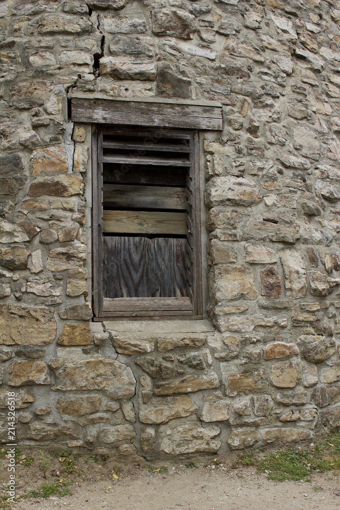 Wood plank window on a very old round stone tower grist mill (windmill) Wood plank window on a very old round stone tower grist mill (windmill)
