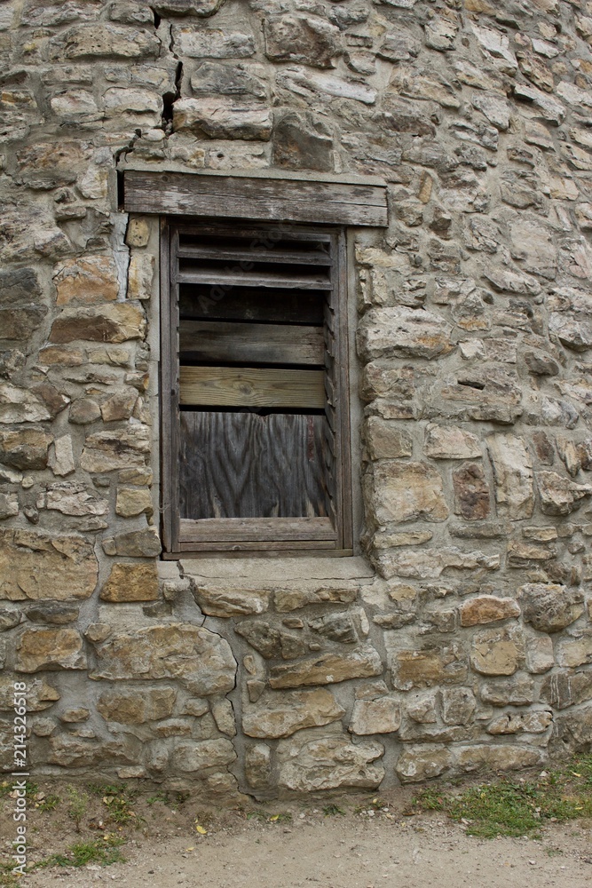 Wood plank window on a very old round stone tower grist mill (windmill)