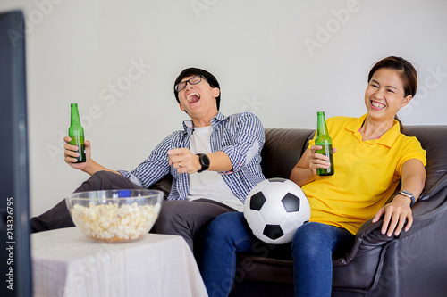 People watch soccer. Asian football supporters watching soccer on television at home with happy emotion. © MIND AND I