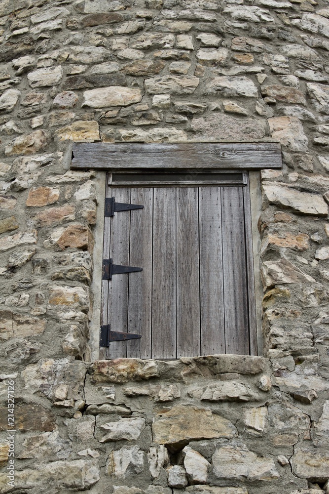 Wood plank window on a very old round stone tower grist mill (windmill) Wood plank window on a very old round stone tower grist mill (windmill)