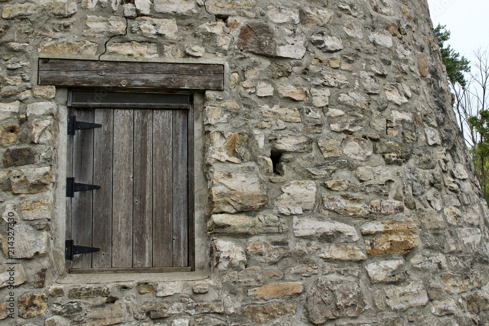 Wood plank window on a very old round stone tower grist mill (windmill) Wood plank window on a very old round stone tower grist mill (windmill)