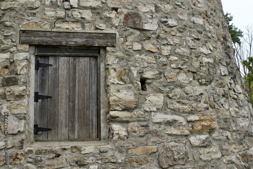 Wood plank window on a very old round stone tower grist mill (windmill) © Cynthia
