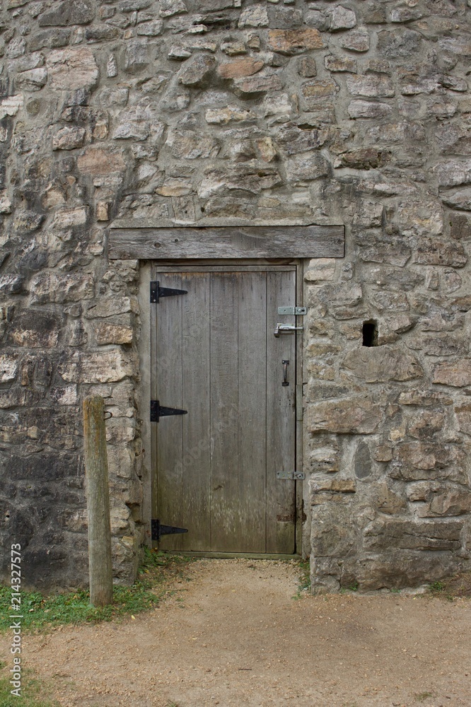 Wood plank entrance door to a very old round stone tower grist mill (windmill)