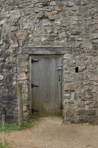 Wood plank entrance door to a very old round stone tower grist mill  windmill 