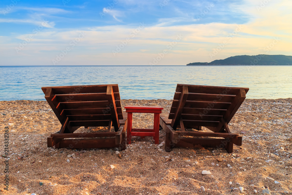 Two empty sunbeds on the beach at Adriatic sea coastline in Montenegro Two empty sunbeds on the beach at Adriatic sea coastline in Montenegro
