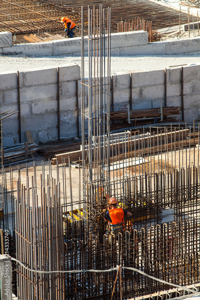 Fototapeta premium Construction of a large commercial building. Worker connects the armature at the construction site