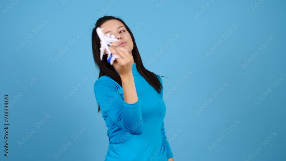 Travel concept of woman playing with a toy airplane on blue background. Freedom and happiness Travel concept of woman playing with a toy airplane on blue background. Freedom and happiness