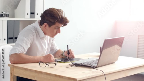 Office work concept. Graphic designer sitting at desk with laptop and tablet photo