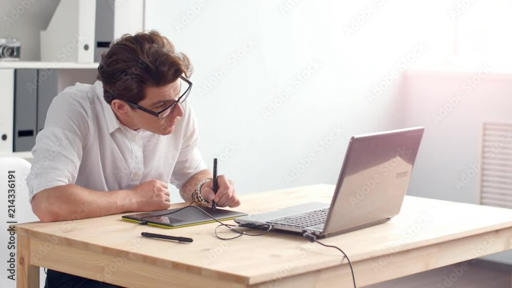 Office work concept. Graphic designer sitting at desk with laptop and tablet Office work concept. Graphic designer sitting at desk with laptop and tablet
