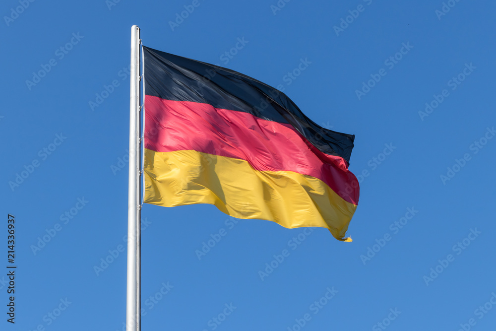 BERLIN, GERMANY, JULY 14, 2018 - German Flag on the flagpole against the blue sky. BERLIN, GERMANY, JULY 14, 2018 - German Flag on the flagpole against the blue sky.