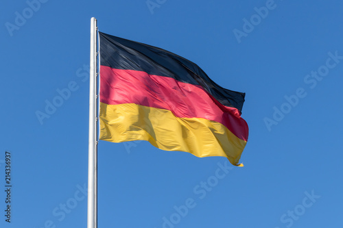 BERLIN, GERMANY, JULY 14, 2018 - German Flag on the flagpole against the blue sky. photo