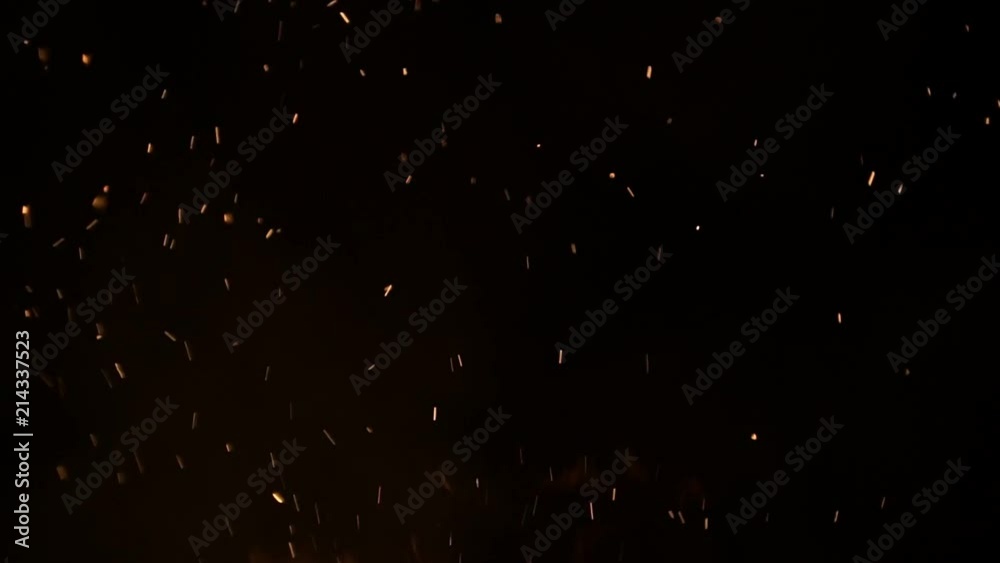 Burning ash rise from large fire in black background